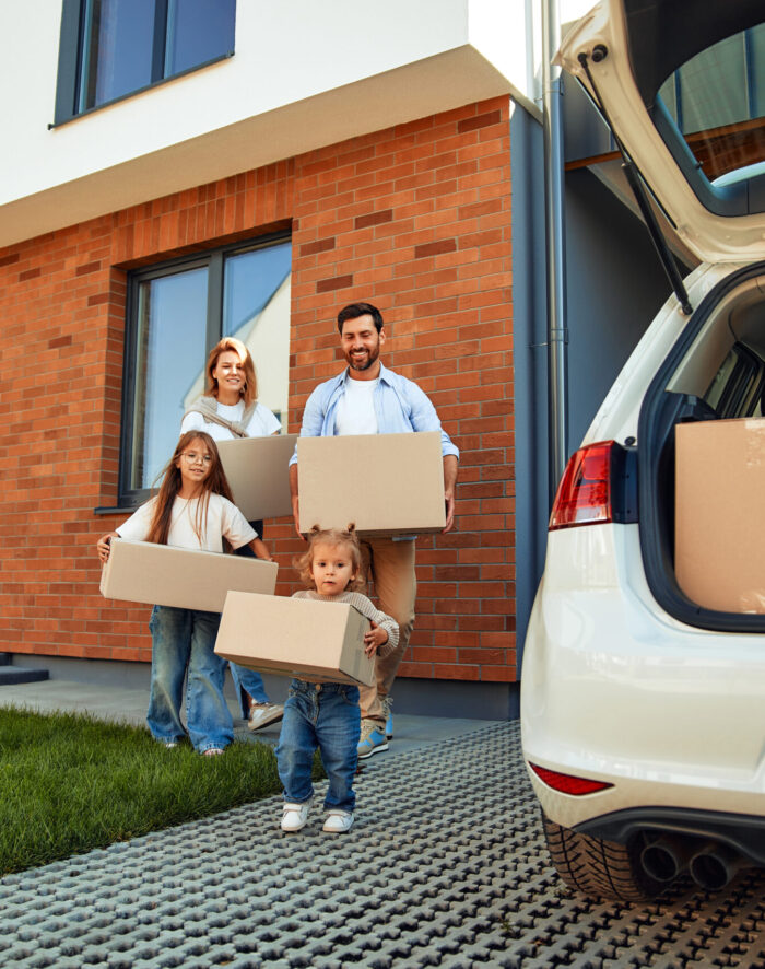 Moving, buying a home. Family shooting. A young family with two children daughters carry boxes of things into the car. Renting and buying a home. Moving to a new home.